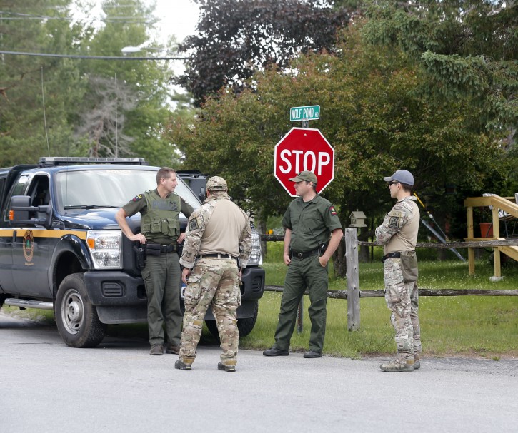 Law enforcement officers stand along a road as the search for two escaped prisoners from Clinton Correctional Facility in Dannemora continues, on Monday, June 22, 2015, in Mountain View, N.Y. (AP Photo/Mike Groll)
