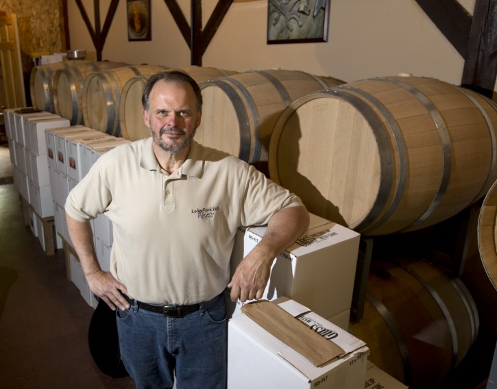 In this Thursday, May 28, 2015 photo, Gary Akrop poses at Ledge Rock Hill Winery and Vineyard in Corinth, N.Y. A host of new grape varieties have enabled a boutique wine industry to take root in areas of the country that were previously inhospitable. In New York, the number of wineries has grown from 35 in 1980 to nearly 500, with the third-highest production in the nation. (AP Photo/Mike Groll)