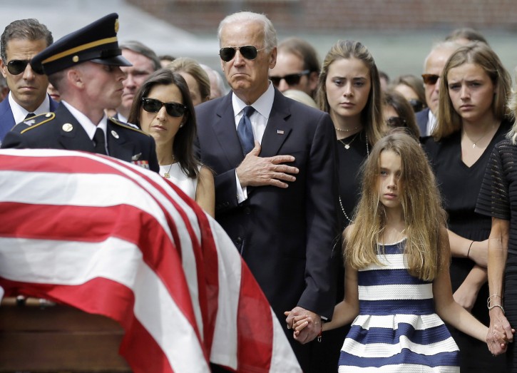 Vice President Joe Biden, accompanied by his family, holds his hand over his heart as he watches an honor guard carry a casket containing the remains of his son, former Delaware Attorney General Beau Biden, into St. Anthony of Padua Roman Catholic Church in Wilmington, Del., Saturday, June 6, 2015, for funeral services. Standing alongside the vice president are Beau's widow Hallie Biden, left, and daughter, Natalie. Beau Biden died of brain cancer May 30 at age 46. (AP Photo/Patrick Semansky)