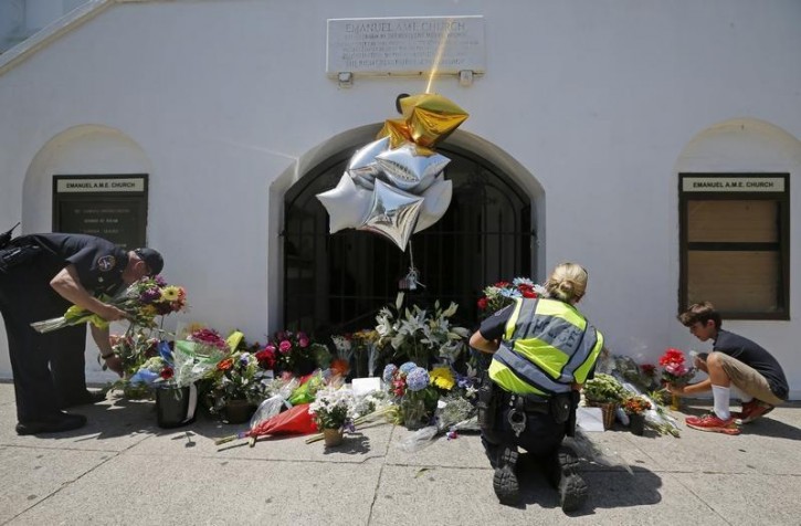 Nine-year-old Liam Eller (R), helps police officers move flowers left behind outside Emanuel African Methodist Episcopal Church after the street was re-opened a day after a mass shooting left nine dead during a bible study at the church in Charleston, South Carolina June 18, 2015.  Reuters