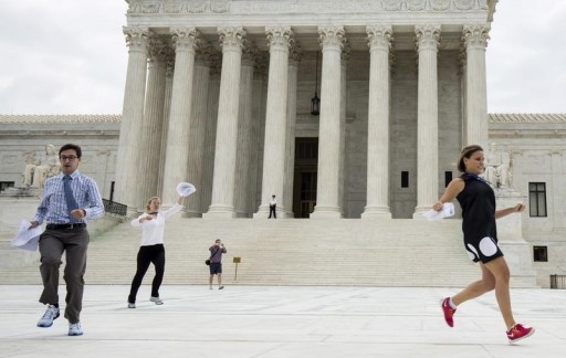 FILE - Interns with media organizations run with the decision that the U.S. Constitution provides same-sex couples the right to marry at the Supreme Court in Washington June 26, 2015. REUTERS