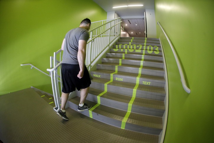 A Utah Valley University student walks up the bright green lanes painted on the stairs to the gym Thursday, June 18, 2015, at Utah Valley University, in Orem, Utah. Utah Valley University spokeswoman Melinda Colton said  the green lanes were intended as a lighthearted way to brighten up the space and get students attention. (AP Photo/Rick Bowmer)