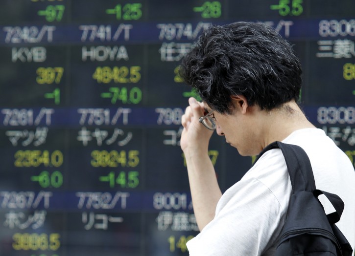 A man walks past an electronic stock board of a securities firm in Tokyo, Monday, July 27, 2015. Asian stock markets were lower Monday as weak Chinese manufacturing accelerated the sell-off in oil and other commodities. Investors were also cautious ahead of the Federal Reserve's policy meeting later this week. (AP Photo/Ken Aragaki)
