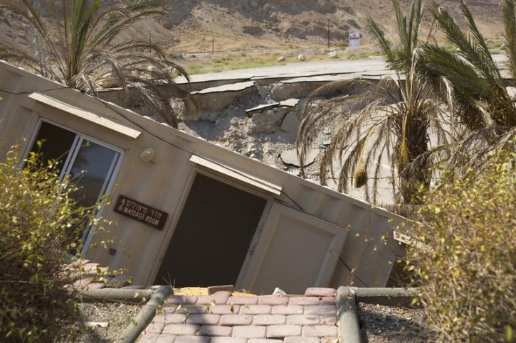 A structure that collapsed into a sinkhole is seen at an abandoned tourist resort on the shore of the Dead Sea, Israel July 28, 2015. The Dead Sea is shrinking, and as its waters vanish at a rate of more than one meter a year, hundreds of sinkholes, some the size of a basketball court, some two storeys deep, are devouring land where the shoreline once stood. Picture taken July 28, 2015. REUTERS/Amir Cohen 