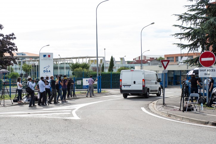 Members of the media watch as a white van, accompanied by police motorcycles and a police car transporting what is believed to be debris from a Boeing 777 plane that washed up on an Indian Ocean island, arrives at Direction Generale de L'armement (DGA) facilities in Balma, near Toulouse, south-western France, Saturday, Aug. 1, 2015. A piece of plane wing that could be from missing Malaysia Airlines Flight 370 arrived Saturday in Toulouse, France, for inspection by military aviation experts.The 6-foot-long part, wrapped in a box and shipped as cargo, was flown from the small island of Reunion, near Madagascar. (AP Photo/Fred Lancelot)