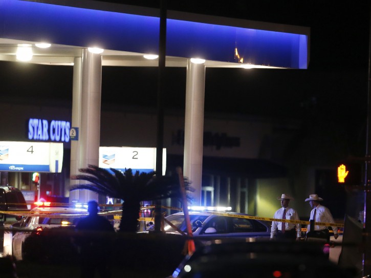 Officials investigate the scene at a gas station where a sheriff's deputy in uniform was fatally shot Friday, Aug. 28, 2015, in Houston. Harris County Sheriff's Office spokesman Ryan Sullivan said the deputy was pumping gas into his vehicle on Friday night when a man approached him from behind and fired multiple shots. (Karen Warren/Houston Chronicle via AP) 