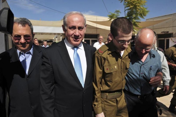 FILE - Gilad Shalit (2nd R) walks with his father, Noam (R), Israel's Prime Minister Benjamin Netanyahu and Defence Minister Ehud Barak (L) at Tel Nof air base in central Israel in this handout released by the Defence Ministry October 18, 2011.REUTERS