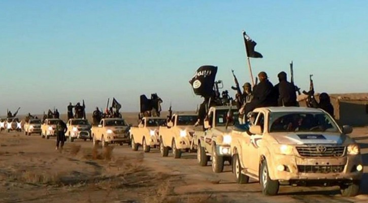 FILE - In this undated file photo released by a militant website, which has been verified and is consistent with other AP reporting, militants of the Islamic State group hold up their weapons and wave flags as they ride in a convoy, which includes multiple Toyota pickup trucks, through Raqqa city in Syria on a road leading to Iraq. Toyota is working with U.S. officials after questions were raised about the prominent use of its vehicles by militant organizations in Syria, Iraq and Libya. (Militant website via AP, File)