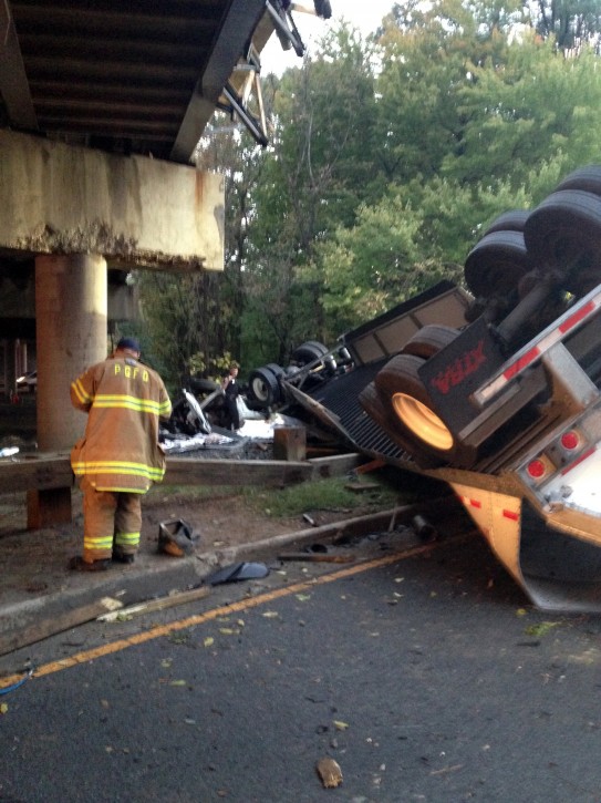 In this photo provided by the Prince Georges County, Md. Fire Department, the wreckage of a tractor trailer lies under an overpass in Suitland, Md., Friday, Oct. 9, 2015. Authorities say a driver was killed when the tractor trailer he was driving fell from a Capital Beltway overpass onto the Suitland Parkway. Maryland State Police say the driver lost control while driving on the outer loop of the beltway early Friday. The truck carrying paper products crashed through the guardrail and landed on the parkway below. (Assistant Fire Chief Alan C. Doubleday/Prince Georges County, Md. Fire Department via AP)
