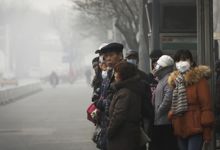 Commuters, some wearing masks to protect themselves from pollutants wait at a bus stand on a heavily polluted day in Beijing, Monday, Nov. 30, 2015. Beijing on Sunday, Nov. 29 issued its highest smog alert of the year following air pollution in capital city reached hazardous levels as smog engulfed large parts of the country despite efforts to clean up the foul air. (AP Photo/Andy Wong)