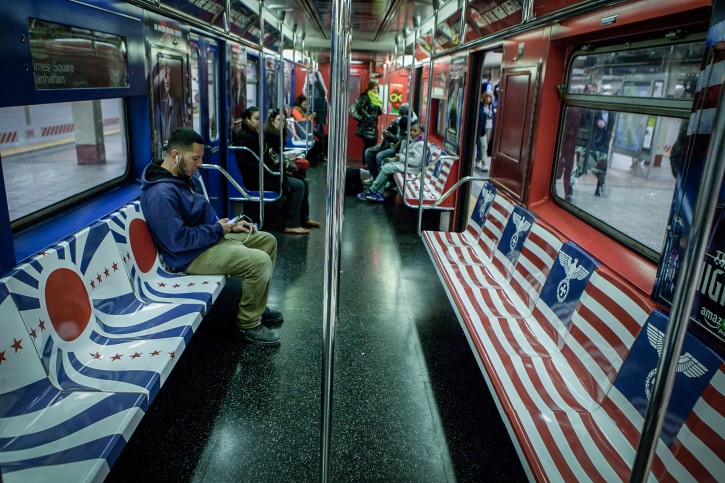 A passenger sits on a bench that is covered with Nazi Germany and Imperial Japan symbols, on the 42nd Street shuttle subway, in New York City, on November 23, 2015. Seats on 42nd Street subway Shuttle cars are wrapped with symbols from Nazi Germany and Imperial Japan, intended to advertise the new Amazon TV series, The Man in the High Castle, in which the Allied Forces lose World War II and the United States is ruled by Nazis. Photo by Amir Levy/Flash90 