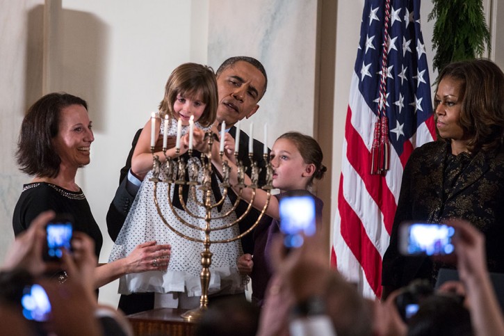 FILE - President Barack Obama holds up Kylie Schmitter as she and her sister Lainey Schmitter light the menorah during the Hanukkah reception #1 in the Grand Foyer of the White House, Dec. 5, 2013. (Official White House Photo by Lawrence Jackson)