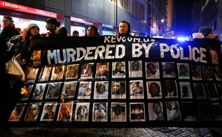 Demonstrators hold a banner during protests in Chicago, Illinois November 24, 2015 reacting to the release of a police video of the 2014 shooting of a black teenager, Laquan McDonald, by a white policeman, Jason Van Dyke. Van Dyke was charged with murder in the incident. REUTERS/Jim Young 