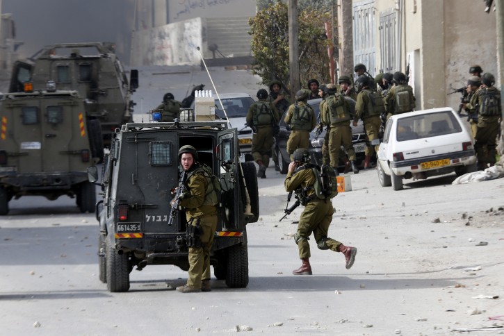Israeli soldiers take up positions during clashes in AL-Fawwar refugee camp, south of Hebron, 26 November 2015. A knife-wielding Palestinian was shot dead at a northern West Bank checkpoint on 26 November and a petrol-bomb thrower was killed in a central West Bank village, as a wave of violence showed no signs of letting up almost two months after it erupted.  EPA/ABED AL HASHLAMOUN