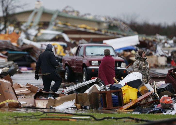 People assess the damage to a storage facility destroyed by Saturday's tornado in Garland, Texas, Sunday, Dec. 27, 2015. Tornadoes that swept through the Dallas area caused substantial damage and at least 11 people died either from the storm or related traffic accidents and dozens of people were injured. (Nathan Hunsinger/The Dallas Morning News via AP)