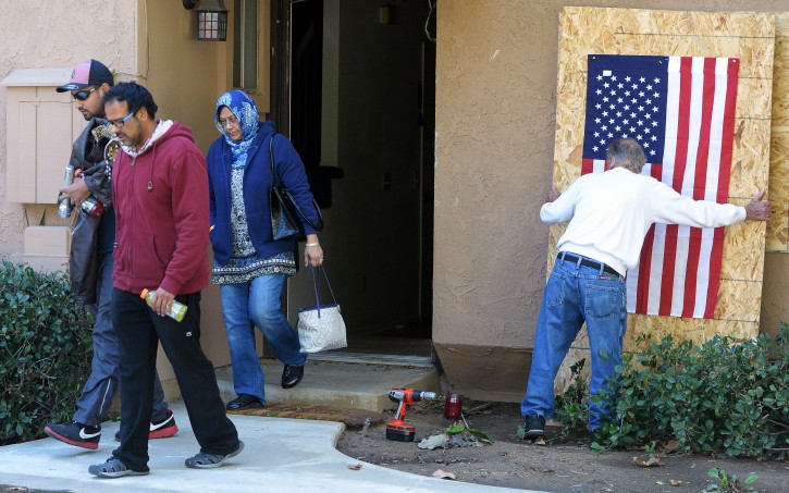 FILE - In this Dec. 19, 2015, file photo, Syed Rizwan Farook's brother Syed Raheel Farook, left, brother-in-law Farhan Khan, second from left, and mother, Rafia Farook, third from left, leave the house of the husband and wife who killed 14 people in San Bernardino, Calif., as landlord Doyle Miller prepares to board up the property in Redlands, Calif. (Will Lester/The Inland Valley Daily Bulletin via AP, File)