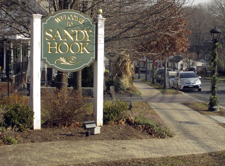 In this Friday, Dec. 11, 2015 photo, a sign welcomes people to the village of Sandy Hook in Newtown, Conn. An interfaith service is planned Monday evening, Dec. 14, on the third anniversary of the shooting at Sandy Hook Elementary School that killed 20 first-graders and six educators. Monday is also the first time the anniversary falls on a school day. (AP Photo/Dave Collins)