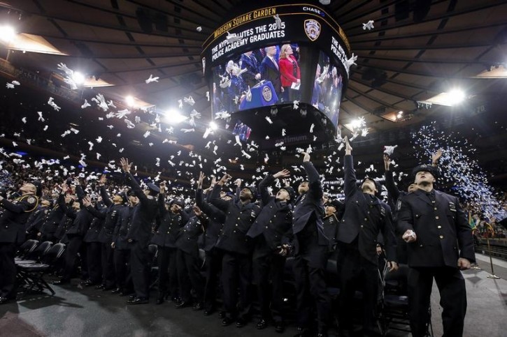 Newly inducted New York Police members throw their ceremonial white gloves in the air as they take part in a graduation ceremony at Madison Square Garden in the Manhattan borough of New York December 29, 2015. According to New York's Mayor Bill de Blasio 1123 new officers graduated onto the force.  REUTERS/Carlo Allegri