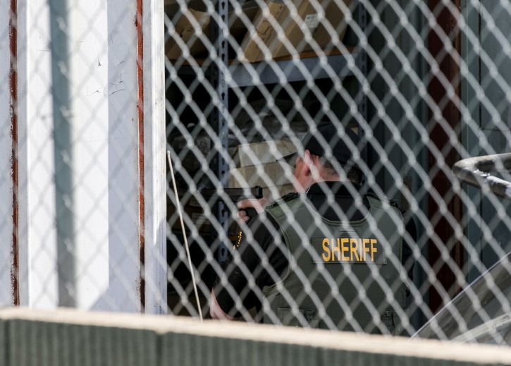 A Orange County Law enforcement agent points his gun inside a container while conducting a search for additional suspects at the back of an auto electric shop garage in Santa Ana, Calif., on Friday, Jan. 29, 2016. Authorities say they have captured all three inmates who escaped from a California jail last week while facing charges involving violent crimes. (AP Photo/Damian Dovarganes)