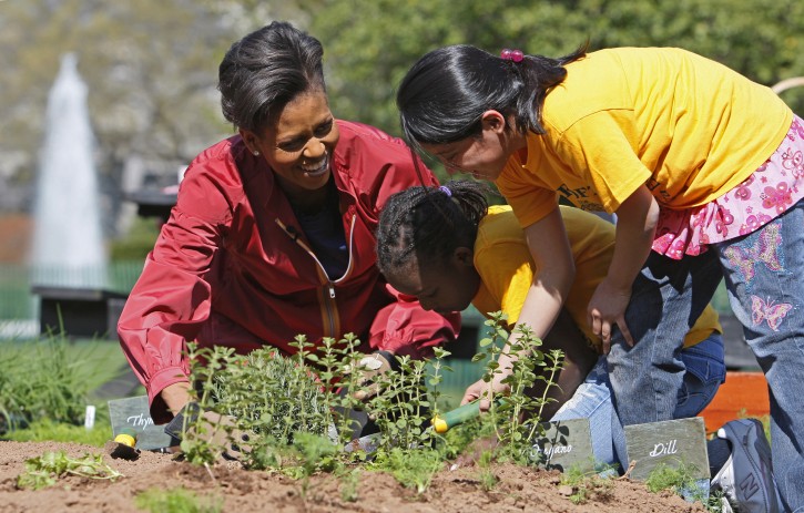 FILE - In this April 9, 2009 file photo, first lady Michelle Obama plants herbs in the White House Kitchen Garden with students from Bancroft Elementary School in Washington, on the South Lawn of the White House in Washington. The South Lawn, for which Mrs. Obama's affection has grown during seven years as first lady, is more than a place to talk about diet and health. It's a symbolic venue for a mother of two from the South Side of Chicago who stepped into the role of presidential spouse with the goal of welcoming more visitors, especially children, to the seat of world power that is the White House. (AP Photo/Charles Dharapak, File)