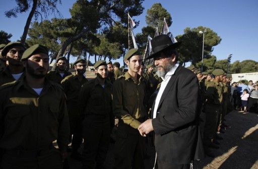 FILE - An Orthodox Jewish man walks past Israeli soldiers of the Netzah Yehuda Haredi infantry battalion during their swearing-in ceremony in Jerusalem May 26, 2013, marking the end of their basic training in the Israeli Defense Forces. REUTERS