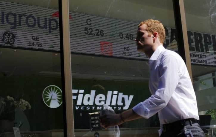 FILE - A pedestrian walks past a stock ticker at a Fidelity Investments office in Boston, Massachusetts July 31, 2013.   REUTERS/Brian Snyder 