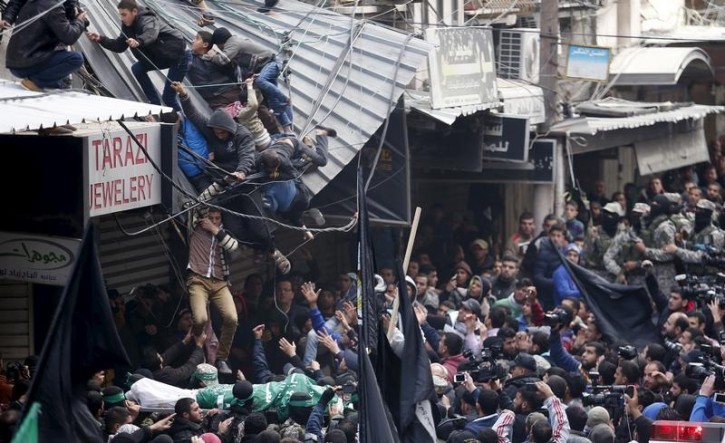 Palestinians fall down from a shop roof during the funeral of seven Hamas gunmen who were killed when a tunnel collapsed close to the Gaza Strip's eastern border with Israel in Gaza City, January 29, 2016. REUTERS/Suhaib Salem