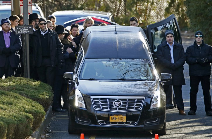 Family members gather at the rear of a hearse carrying the casket during the funeral for Dr. Robin Goldman, a 58-year-old pediatrician found slain inside her multimillion-dollar Scarsdale, N.Y., home Thursday, Jan. 21, 2016, in New Rochelle, N.Y.  Goldman's husband Jules Reich, 61, a New York-based tax specialist, has been charged with second degree murder in connection with the case, according to local police.  (AP Photo/Kathy Willens)