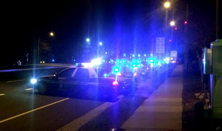More than 100 patrol cars line the roads outside Inova Fairfax Hospital early Sunday morning, Feb. 29, 2016, to stand vigil and provide escort to the medical examiner for the body of slain Prince William County police officer Ashley Guindon, who was shot and killed Saturday responding to a domestic violence call. Two other officers were also shot and taken to the hospital. Guindon had been sworn in as an officer on Friday. (AP Photo/Matthew Barakat)