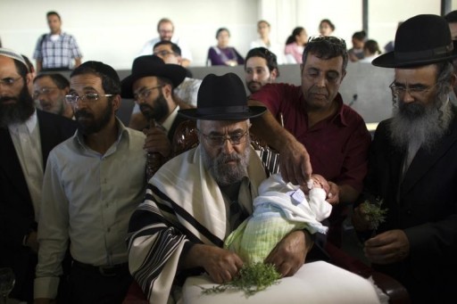 FILE - A Jewish man holds his grandson after his 'Bris in Neve Ilan near Jerusalem September 24, 2012.REUTERS