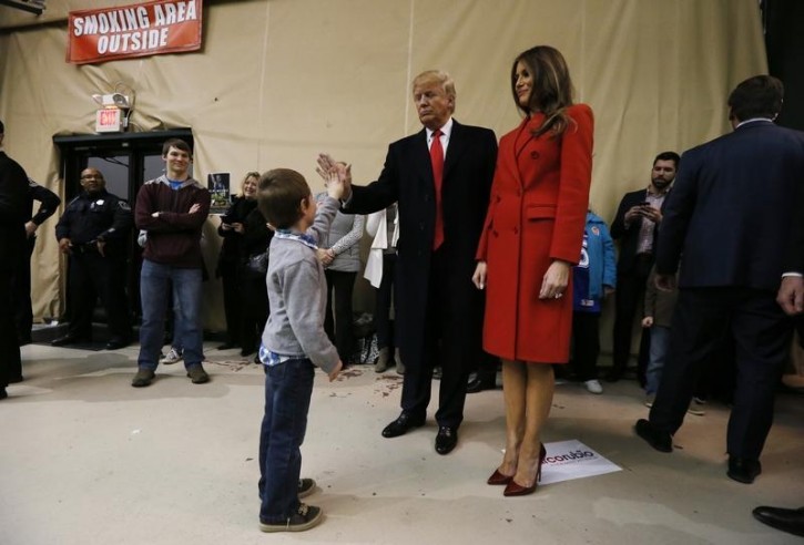 A young boy high-fives Republican Presidential candidate Donald Trump as his wife Melania watches as the candidate waits at the Seven Flags Event Center in Clive, Iowa February 1, 2016.  REUTERS/Jim Bourg 