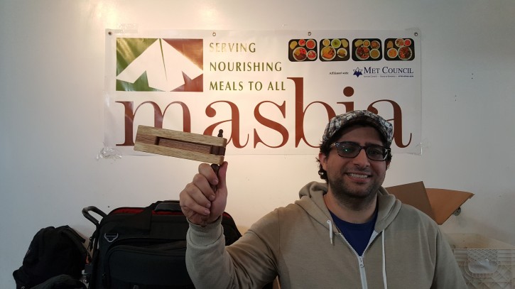 Brooklyn artist Alex Aronov holding up a handmade Grogger he createted using old tables that were no longer in use at Masbia