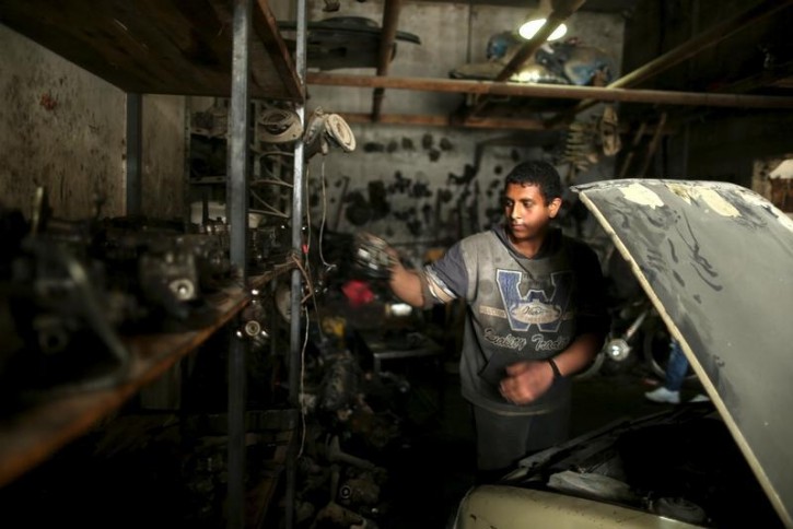 Palestinian boy Mohamoud Yazji, 16, who works as apprentice mechanic, repairs a car at a garage in Gaza City March 17, 2016. Yazji, whose father works as a tailor, earns 50 Shekels ($12.9) a week to help his father support their family. The boy, who quit school, hopes to own a garage in the future. REUTERS/Mohammed Salem 