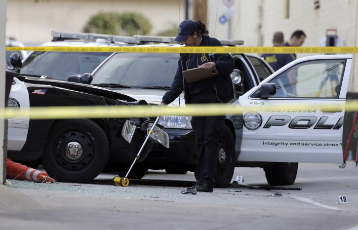 Police investigate the officer-involved shooting that happened at the end of a car pursuit in Glendale, Calif., on Monday, March 14, 2016. The driver hit speeds topping 100 mph during the pursuit that was broadcast live on news stations Sunday night. Police shot and killed a suspect who stole a West Covina patrol car, partially seen left, and led officers on an hour-long chase across Southern California freeways that ended when an officer in an SUV slammed into the stolen vehicle in the alley, pinning the suspect inside as he gunned the engine, trying to escape again. Police opened fire, killing the 45-year-old man at the scene, authorities said. (AP Photo/Nick Ut)