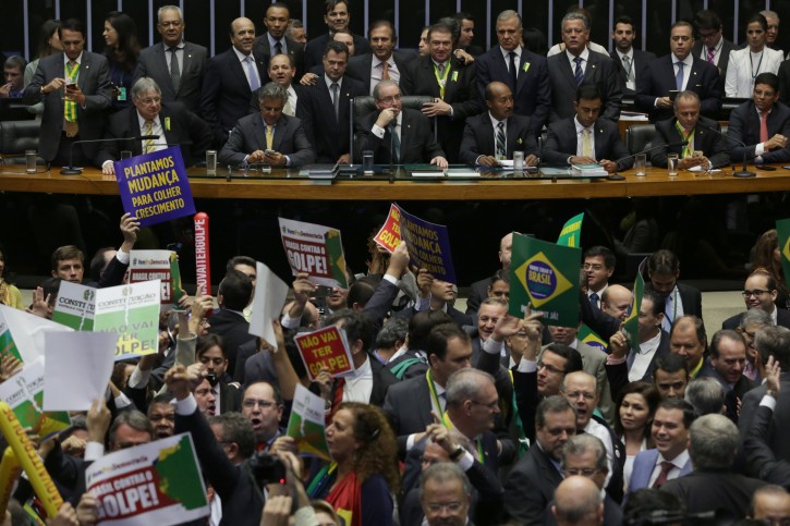President of the Chamber of Deputies Eduardo Cunha, center on the table, starts the session on whether or not to impeachment President Dilma Rousseff, in Brasilia, Brazil, Sunday, April 17, 2016. The vote will determine whether the impeachment proceeds to the Senate. Rousseff is accused of violating Brazil's fiscal laws to shore up public support amid a flagging economy. (AP Photo/Eraldo Peres)