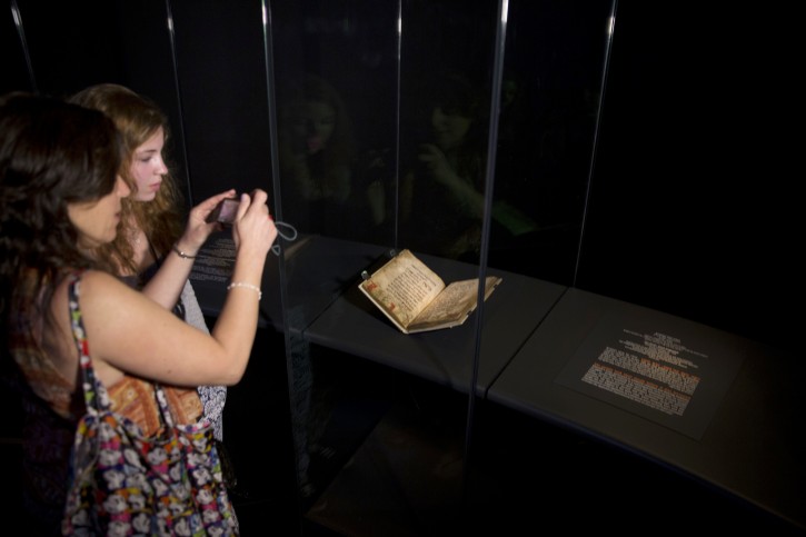In this photo taken Wednesday, April 20, 2016, visitors look at the famed Birds' Head Haggadah, a medieval copy of a text read around the Passover holiday table, on display at the Israel Museum in Jerusalem. The grandchildren of one of the earliest Jewish victims of the Nazis are laying claim to a jewel of Israel's top museum: the world's oldest surviving illustrated Passover manuscript. (AP Photo/Sebastian Scheiner)