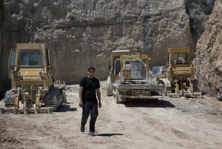 In this Tuesday, April 19, 2016 photo, 25 year-old, Alaa Al-Tawil, walks through a Palestinian quarry in the West Bank village of Beit Fajar, Bethlehem. The economic future of the Palestinian town of Beit Fajar looks bleak after Israel's military shut some three dozen quarries and put 3,500 jobs at risk, paralyzing the dominant local industry. (AP Photo/Nasser Nasser)