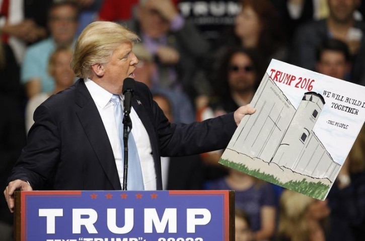 FILE - U.S. Republican presidential candidate Donald Trump holds a sign supporting his plan to build a wall between the United States and Mexico that he borrowed from a member of the audience at his campaign rally in Fayetteville, North Carolina March 9, 2016. Trump was interrupted repeatedly by demonstrators during his rally.    REUTERS/Jonathan Drake -