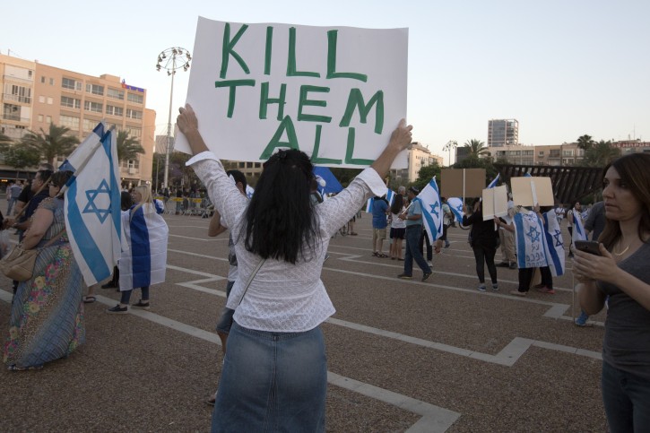 FILE - A woman holds up a placard that reads 'Kill Them All', as people gather in Rabin Square in Tel Aviv, Israel, 19 April 2016