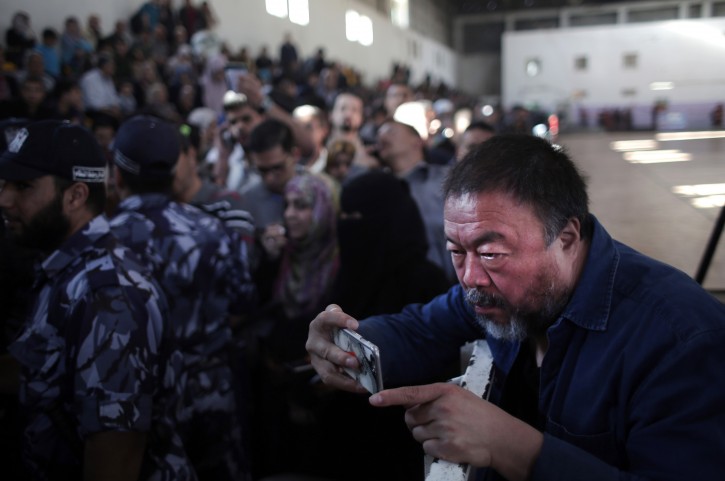 Chinese film director, Ai Weiwei, films using his mobile phone Palestinians wait their turn to travel through the Rafah border crossing with Egypt, in the southern Gaza Strip, , Wednesday, May 11, 2016. (AP Photo/ Khalil Hamra)