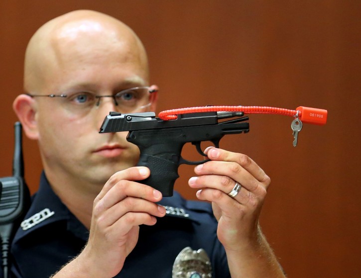 FILE- In this June 28, 2013 file photo, Sanford police officer Timothy Smith holds up the gun that was used to kill Trayvon Martin, while testifying in the George Zimmerman trial, in Seminole circuit court in Sanford, Fla. The pistol former neighborhood watch volunteer George Zimmerman used in the fatal shooting of Trayvon Martin is going up for auction online. (AP Photo/Orlando Sentinel, Joe Burbank, Pool, File)