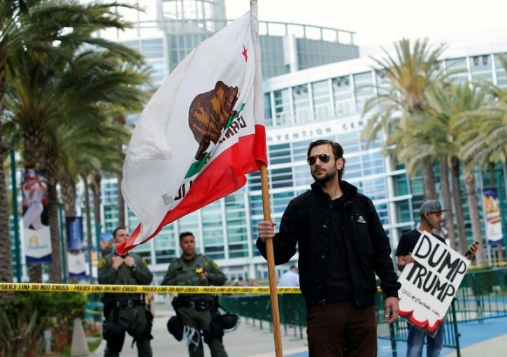 A man holds the state flag of California outside Anaheim Convention Center, where Republican U.S. Presidential candidate Donald Trump will speak at a campaign event in Anaheim, California U.S. May 25, 2016.  REUTERS/Mike Blake 