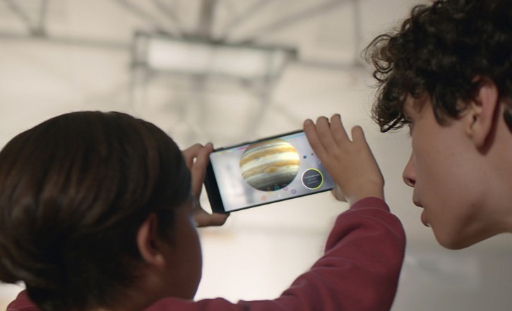 This image provided by Google shows people looking at a view of the solar system using technology Google calls "Project Tango." Tango uses software and sensors to track motions and size up the contours of rooms, which can empower a smartphone to map building interiors. Thats a crucial building block of a promising new frontier in augmented reality, or the digital projection of lifelike images and data into a real-life environment. (Courtesy of Google via AP)