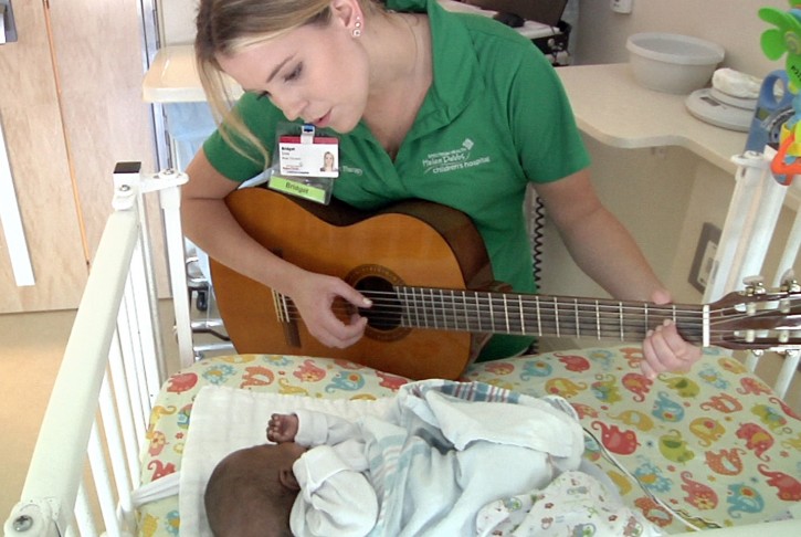 In this Friday, June 17, 2016, image made from video, Bridget Sova, music therapist at the Helen DeVos Children's Hospital, sings to Aubrey Spearman inside the infant's room at the hospital in Grand Rapids, Mich. Sova records the heartbeats of young patients and sets the sounds to music as a memory-making gift for parents and other loved ones. (AP Photo/Mike Householder)