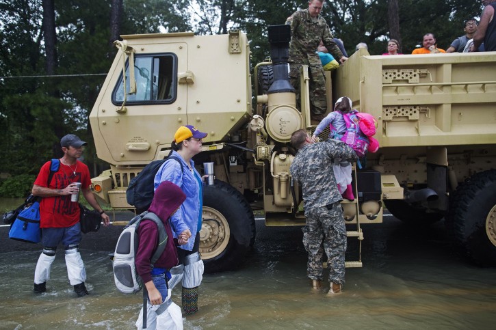 Kevin Richmond, left, and Barbara Manuel and her two children Elliott, age 8, and, center, and Emily, age 5, right, are rescued by members of the Louisiana Army National Guard from rising flood water near Walker, La., after heavy rains inundating the region, Sunday, Aug. 14, 2016. (AP Photo/Max Becherer)