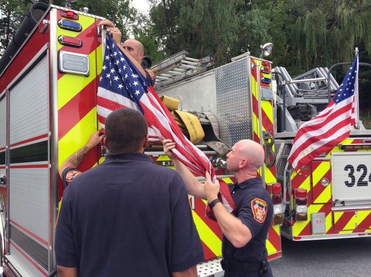 In this Tuesday, Aug. 16, 2016 photo, firefighters remove American flags from a fire truck in Poughkeepsie, N.Y. Fire Commissioners Board Chairman Jim Beretta says the board saw the flags as a "liability during normal operations for our people and other motorists." The flags were recently put up at the request of the union. Fire Chief Tory Gallante says he's "very disappointed" with the order. (Nina Schutzman/Poughkeepsie Journal via AP)