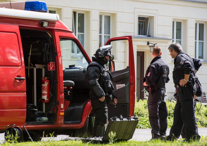 Police guard in front of a house in Eisenhuettenstadt, Germany,  Wednesday Aug. 17, 2016. German police arrested a man Wednesday after finding explosives during a raid on his apartment and authorities said he is suspected of planning an attack. The suspect is a 27-year-old German man who lived in the eastern city of Eisenhuettenstadt, Frankfurt an der Oder police told the dpa news agency.  (Patrick Pleul/dpa via AP)