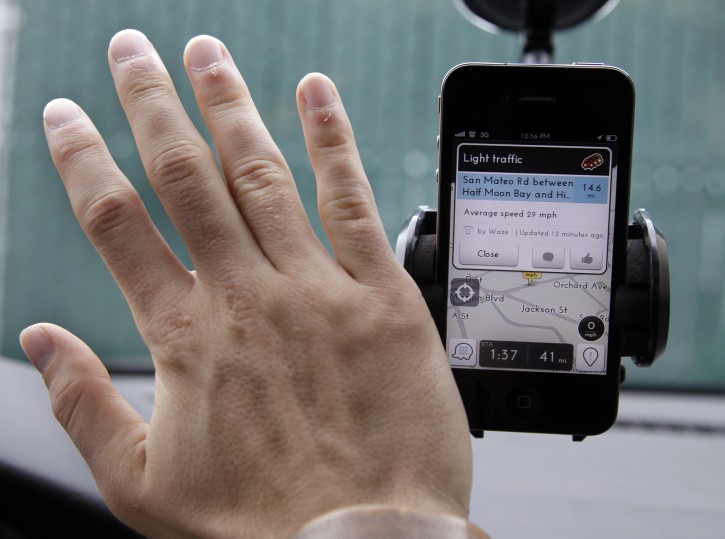 FILE- In this March 15, 2012, file photo, Ben Gleitzman waves his hand over a traffic and navigation app called Waze on his Apple iPhone in a Menlo Park, Calif., parking lot during a demonstration showing traffic conditions on the display. (AP Photo/Paul Sakuma, File)