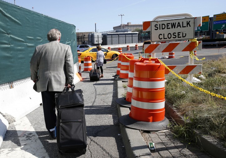 In this Wednesday, Aug. 24, 2016, photo, arriving passengers haul their suitcases down a pathway toward temporary taxi stand outside of Terminal B at LaGuardia Airport in New York. Since Monday's traffic congestion debacle, Port Authority officials and others participating in the airport's $4 billion renovation, are trying to cope with traffic congestion that has impacted travelers trying to get to and from the airport. (AP Photo/Kathy Willens)