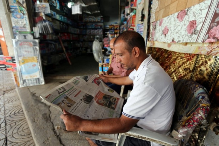 A Palestinian man reads a newspaper outside his store in Gaza City September 19, 2016.  REUTERS/Ibraheem Abu Mustafa